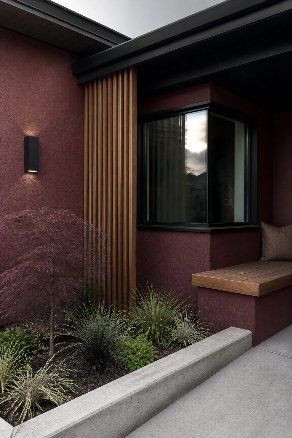 Modern home with maroon walls, black window, wood slats, bench, and garden.