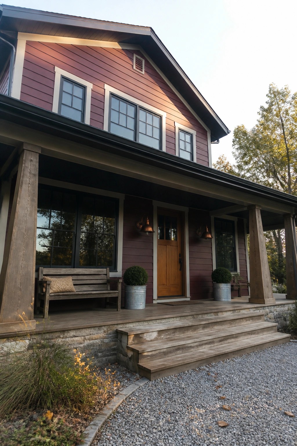 A two-story house with deep red horizontal siding, a wooden front door, and a front porch supported by thick wooden posts.