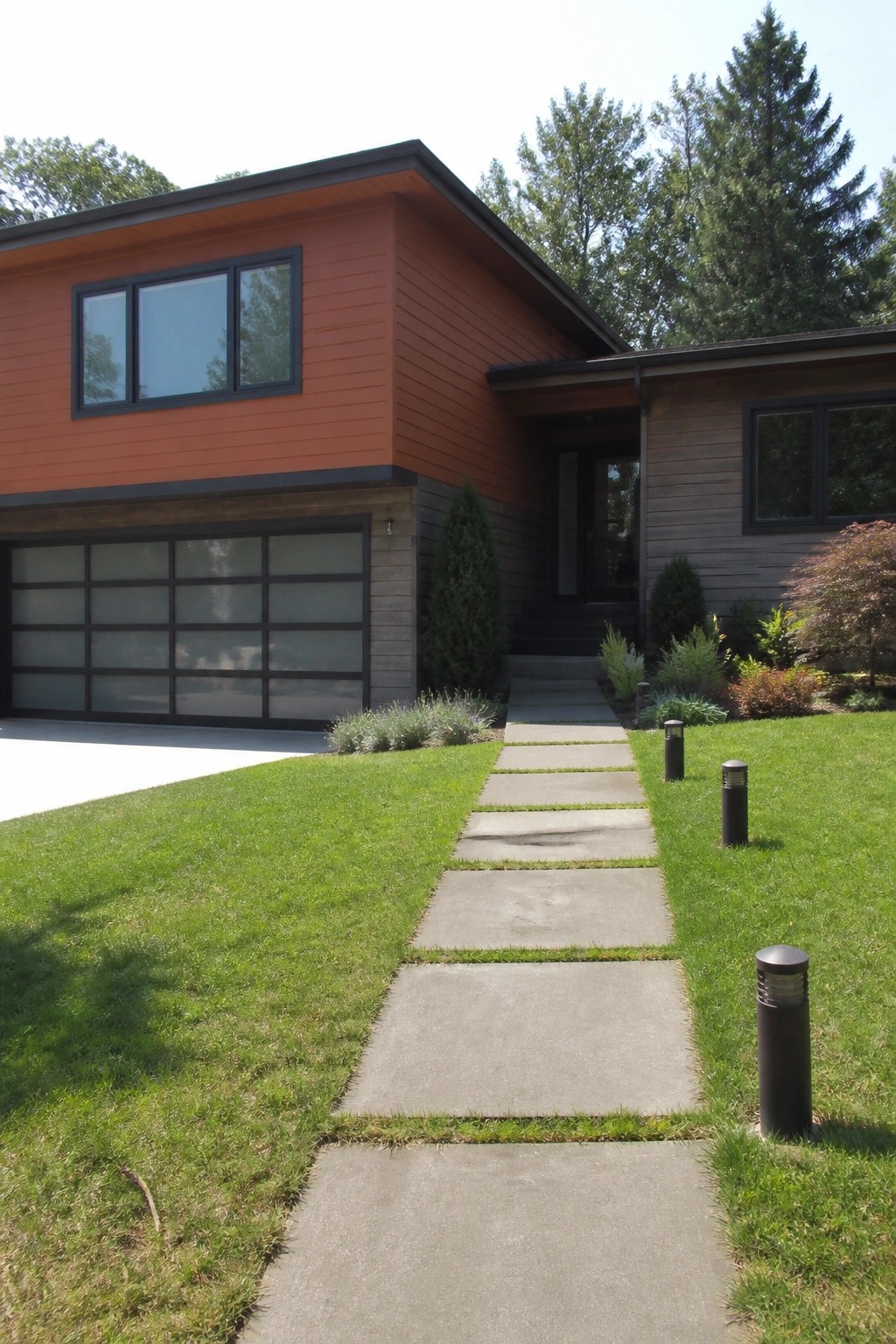 A modern two-story house with burnt orange lap siding on the upper level, wood accents below, and a concrete walkway across a green lawn.