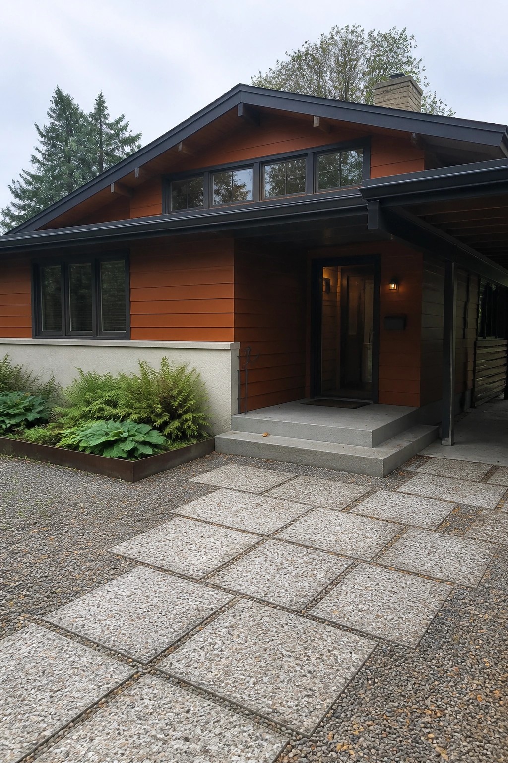A house with burnt orange horizontal lap siding, dark trim, concrete steps, and a gravel driveway in front.