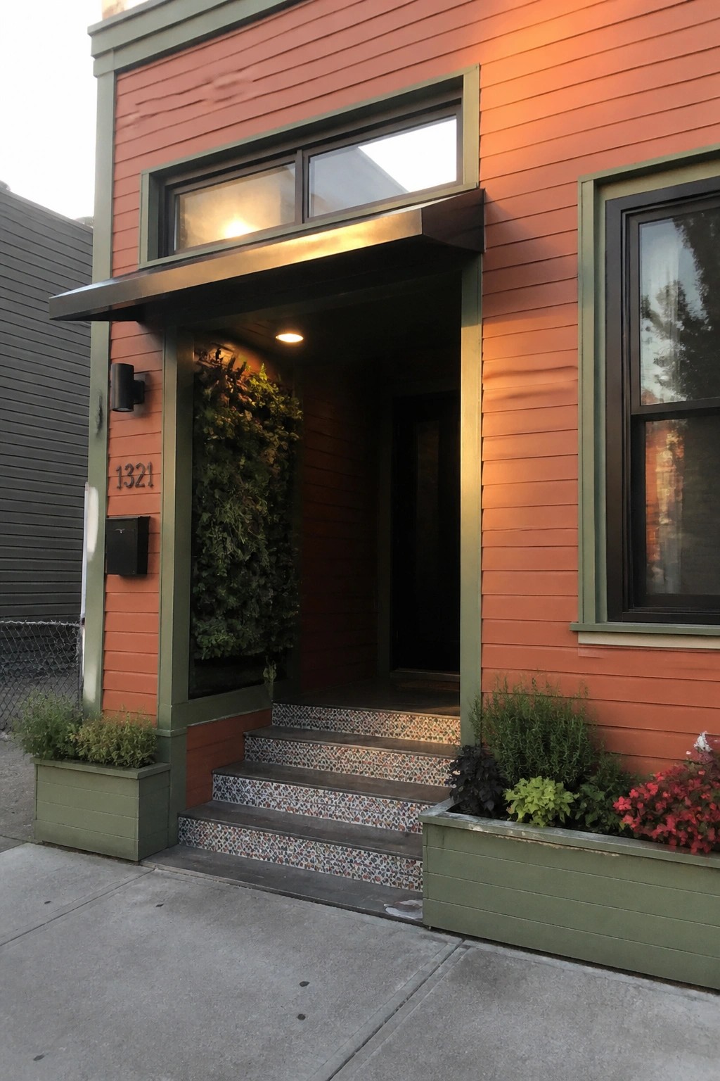 Front view of a house with burnt orange lap siding, green trim, a recessed entry, and tiled steps.