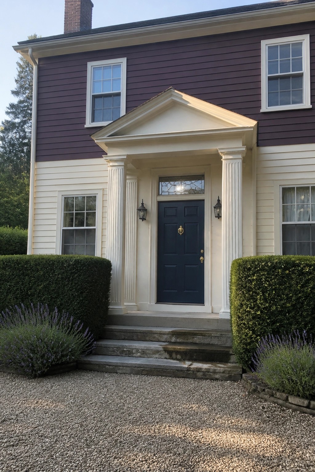 A two-story house with aubergine siding, white columns, and a pediment framing a dark blue door.