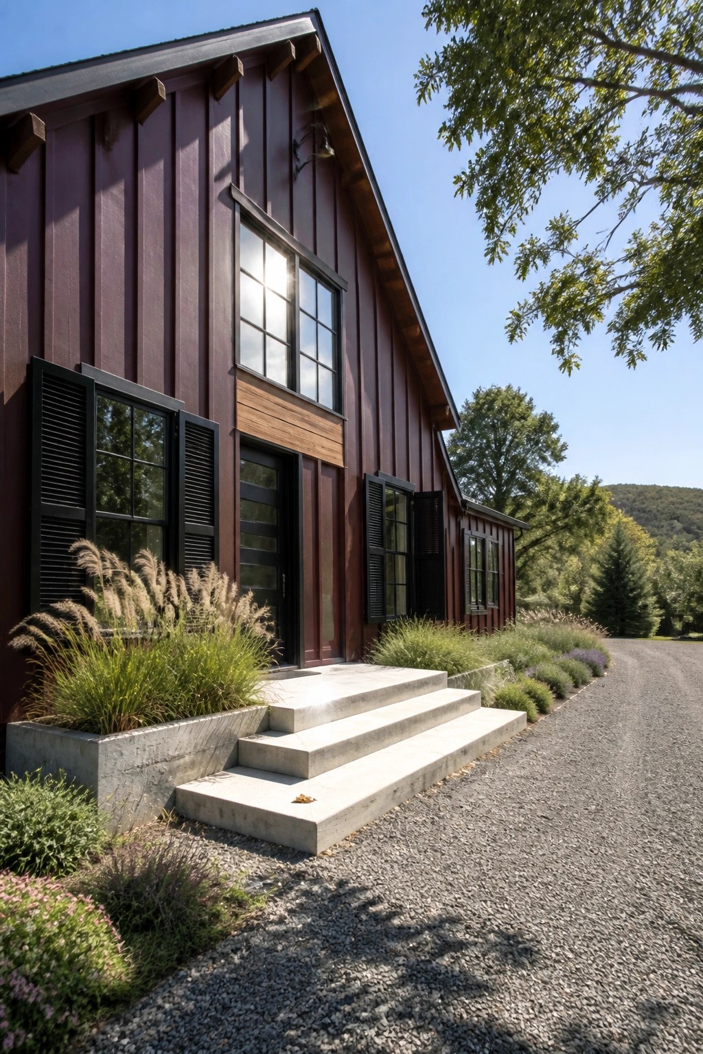 A house exterior with deep burgundy vertical siding, black shutters on several windows, black window frames, a dark front door, and concrete steps leading up to it.