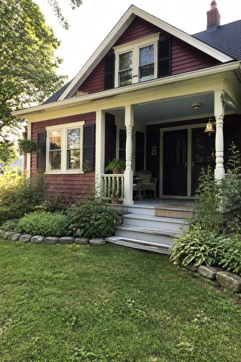 A burgundy house exterior with black shutters, white trim, and a front porch with light blue ceiling.