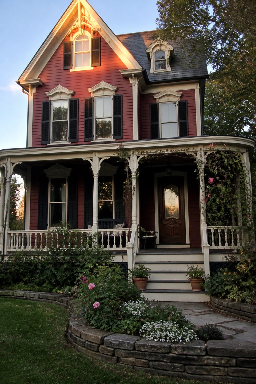 A two-story house with deep burgundy siding, black shutters, white trim, and a wraparound porch.