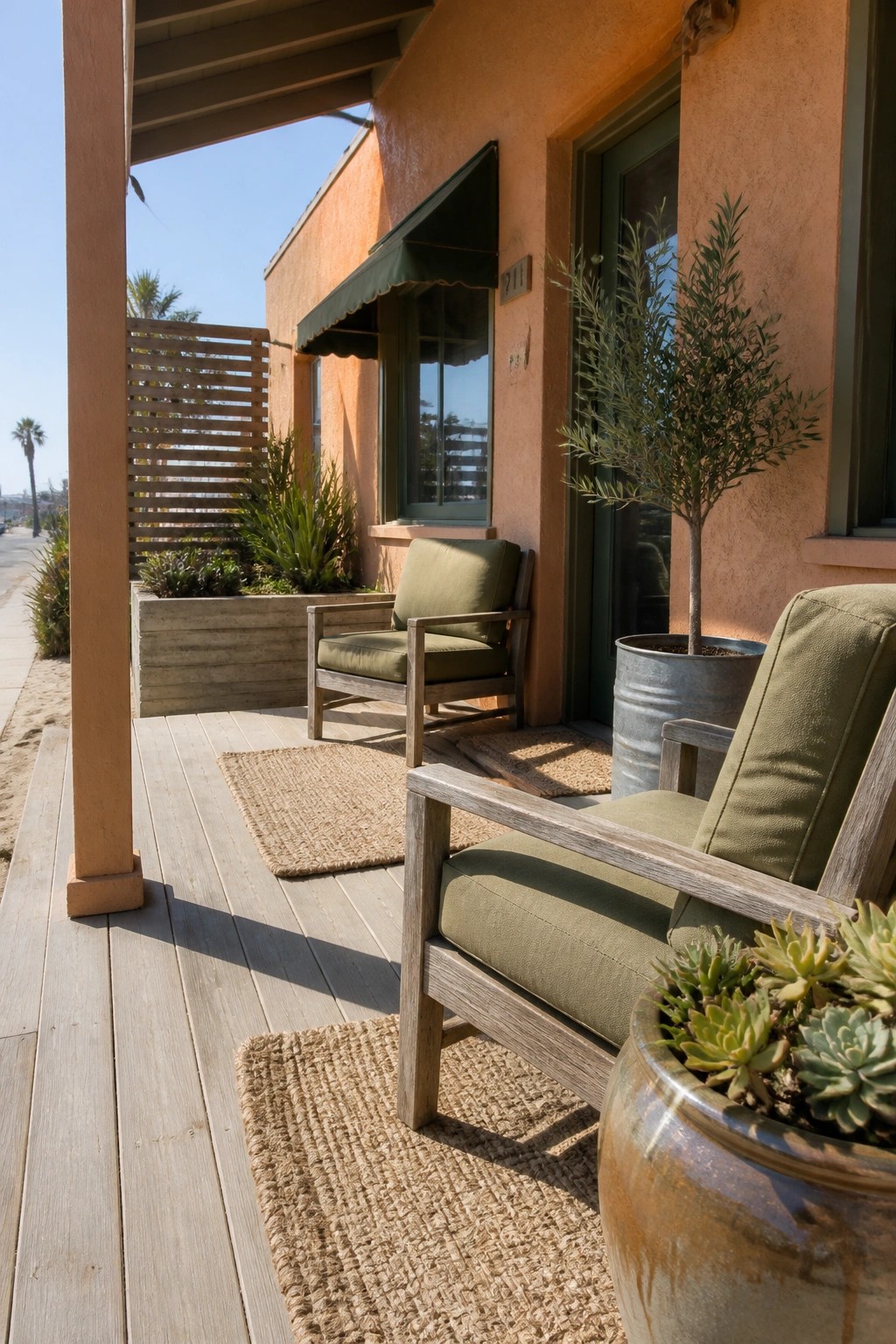 Sunny wooden porch with green-cushioned chairs, woven rugs, and potted succulents by orange wall