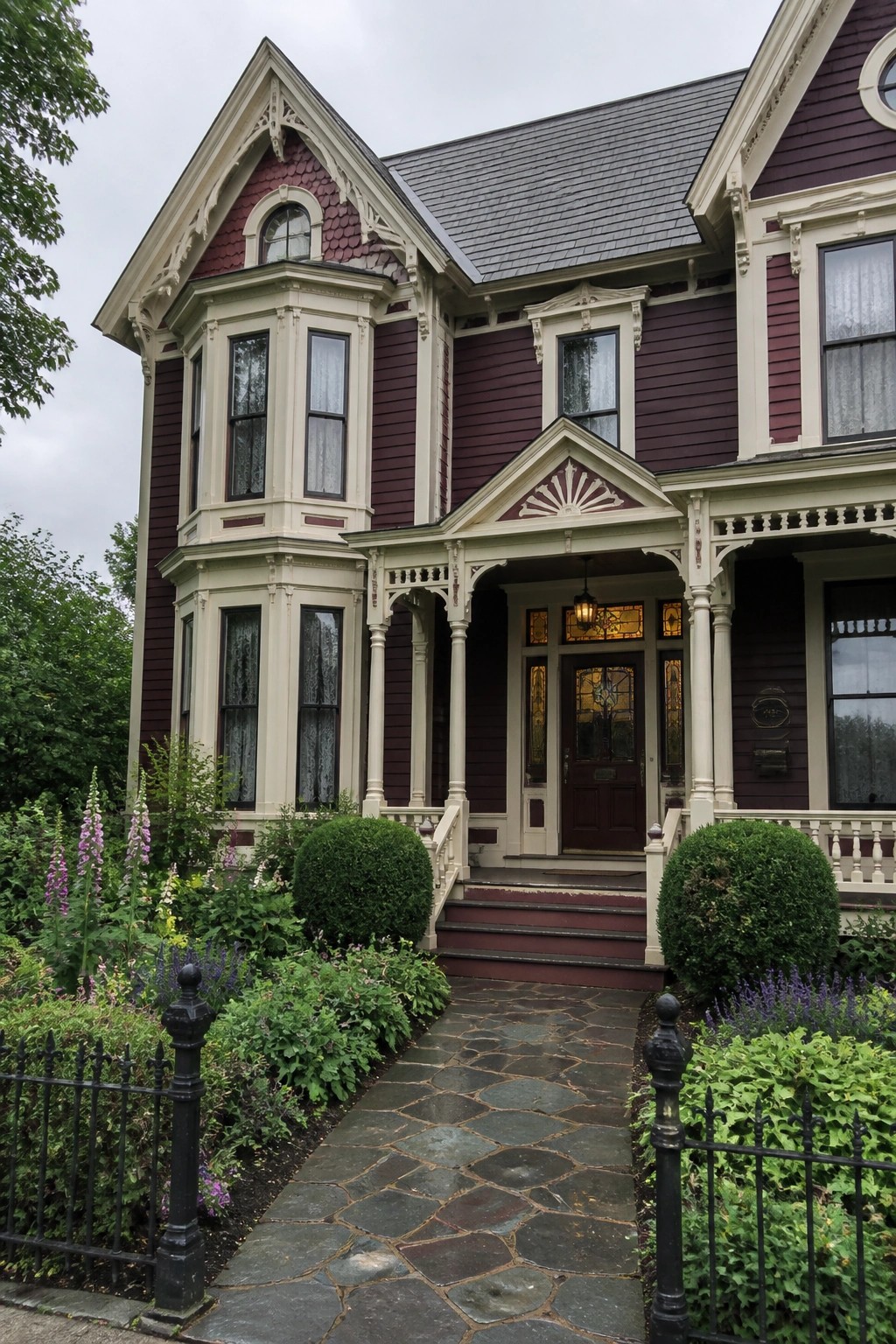 Victorian house with purple siding, cream trim, stone path, and lush garden.