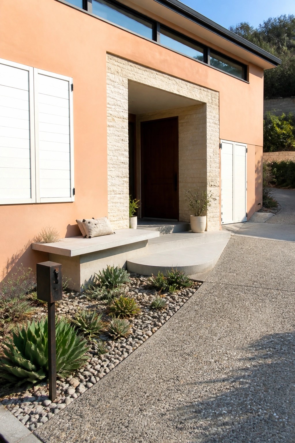 Peach stucco house exterior with white shutters on a window, a stone-framed entry, and a concrete bench beside the door.