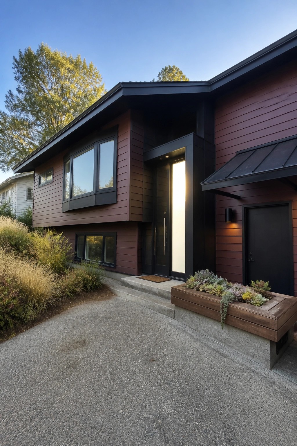 Modern house with dark red siding, black trim, large windows, and wooden planter.