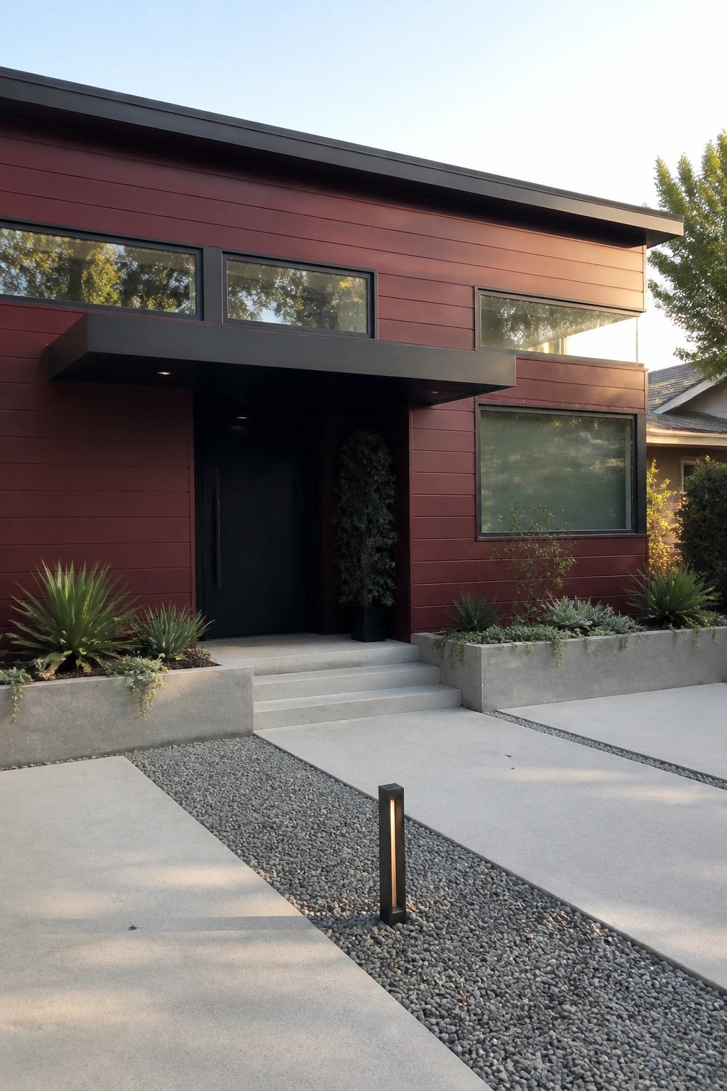 Modern house exterior with maroon horizontal siding, matte black trim, black door, and concrete entry steps.