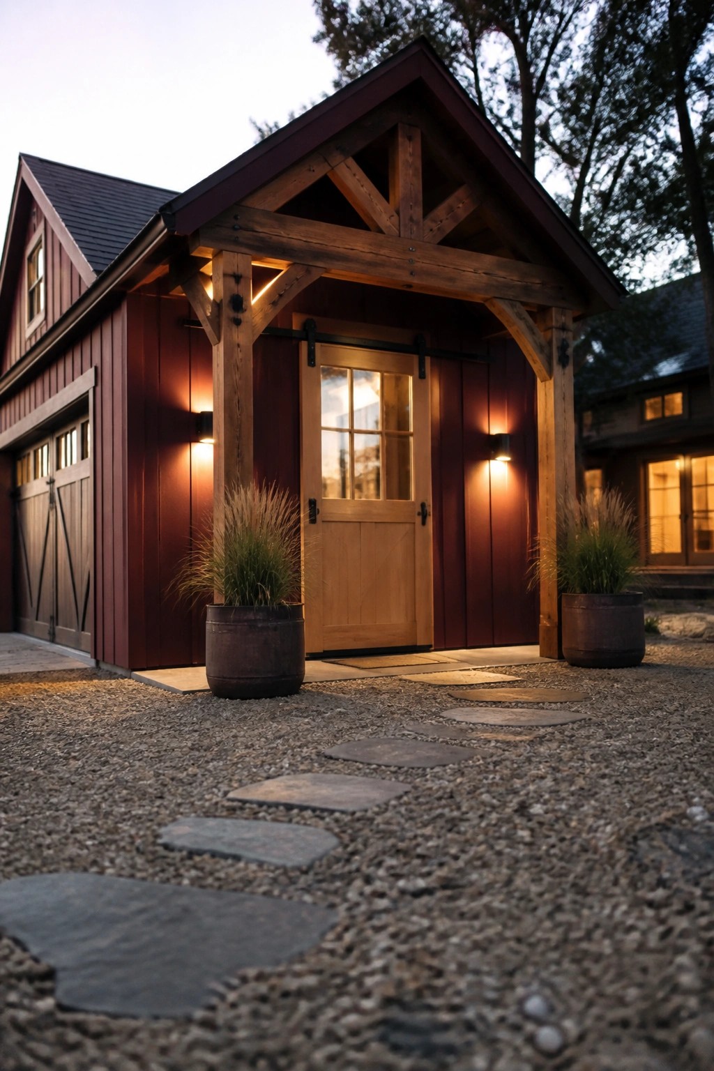 A burgundy wooden house exterior with a timber-framed porch, light wood door, and gravel path of stepping stones.