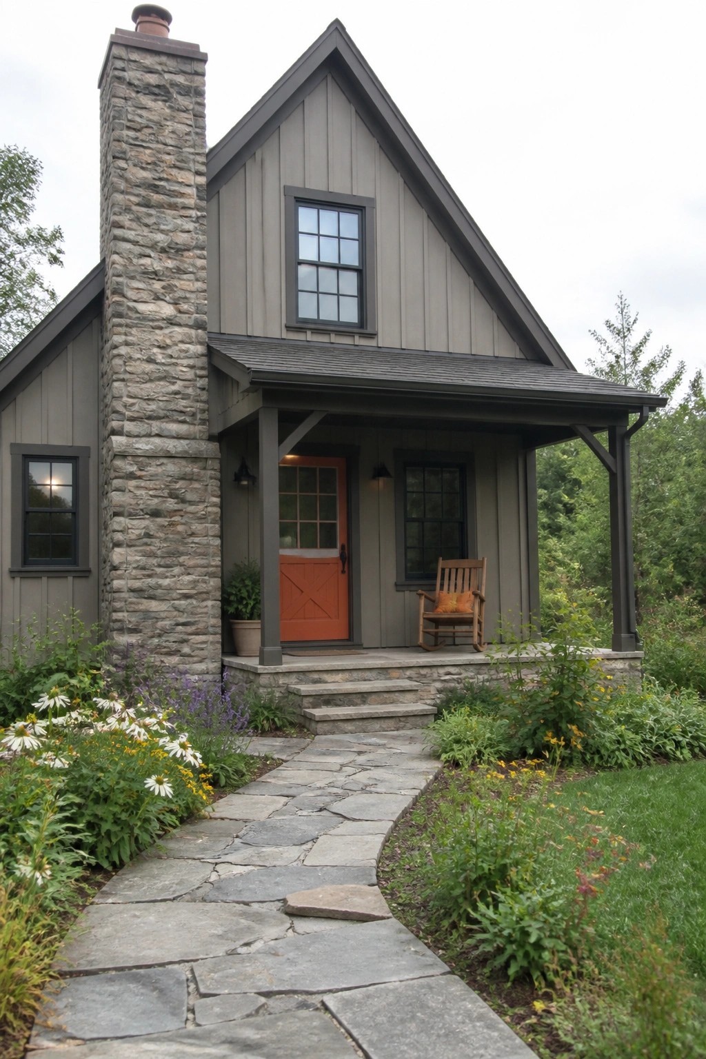 A gray house exterior with stone chimney, orange front door, and stone pathway leading to the porch.