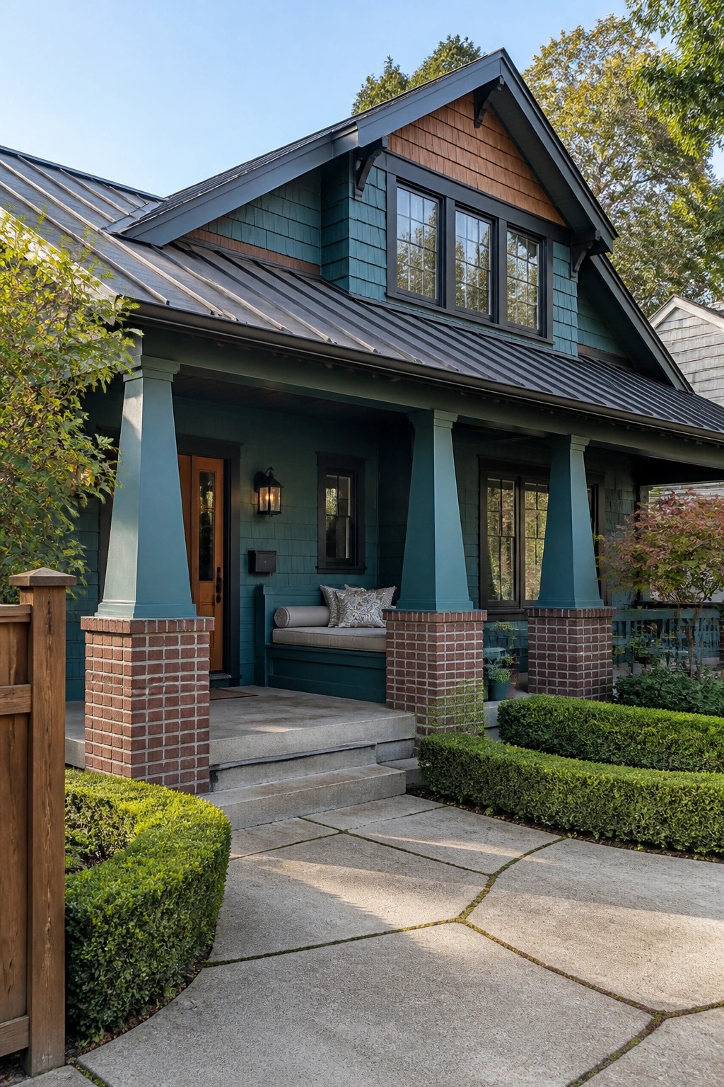 Teal Craftsman house with a front porch supported by tapered columns on brick piers and a metal roof.