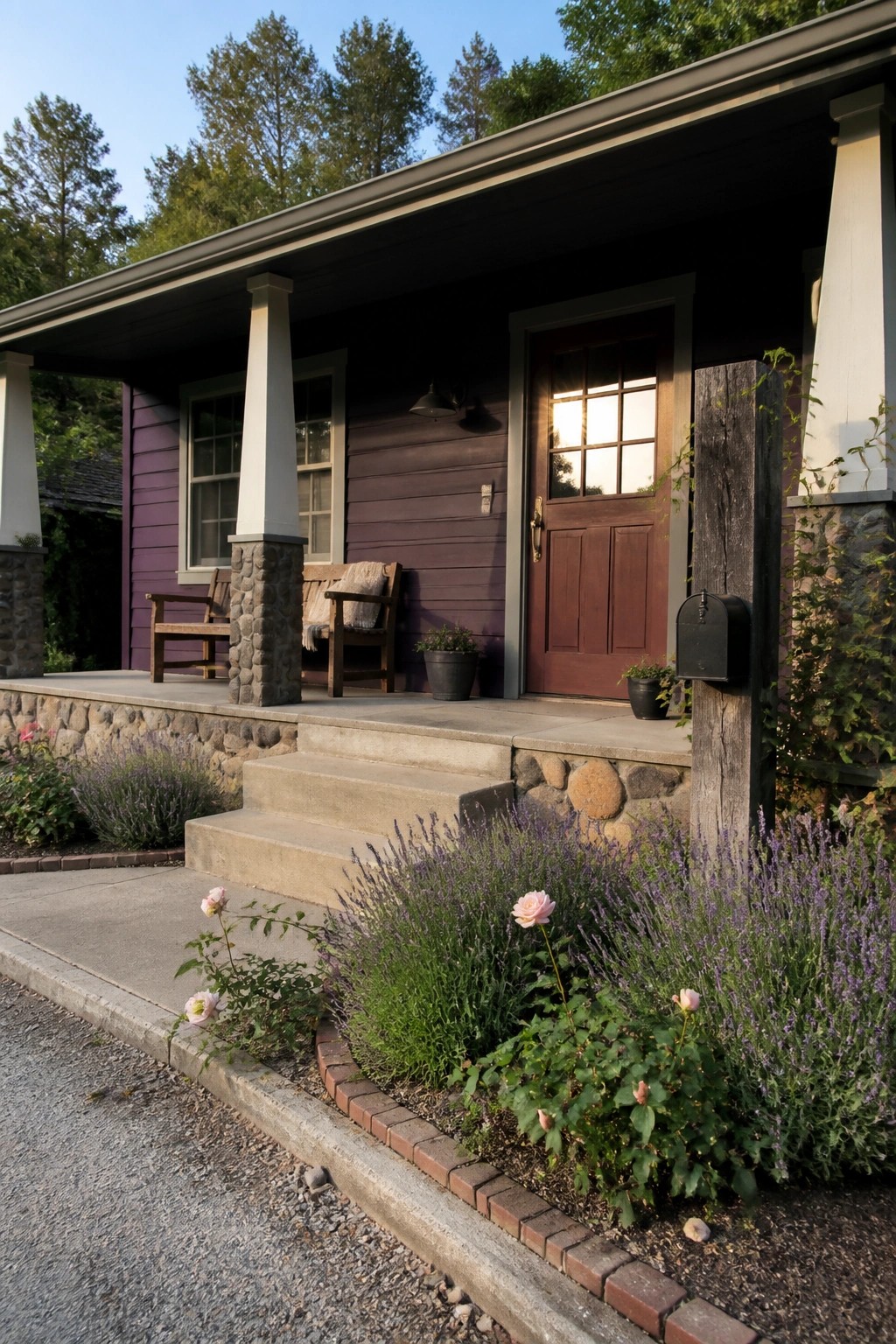 A single-story house with plum siding, stone porch pillars, a wooden front door, and concrete steps bordered by lavender and roses.