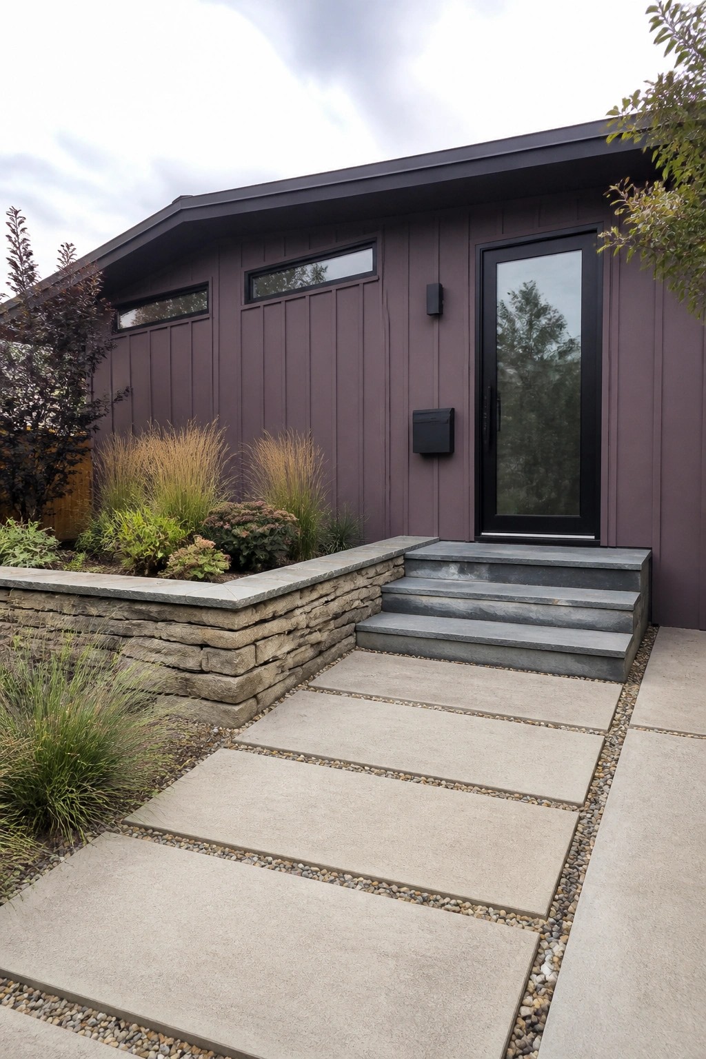 Dark purple house with black door, stone steps, retaining wall, and paver path.