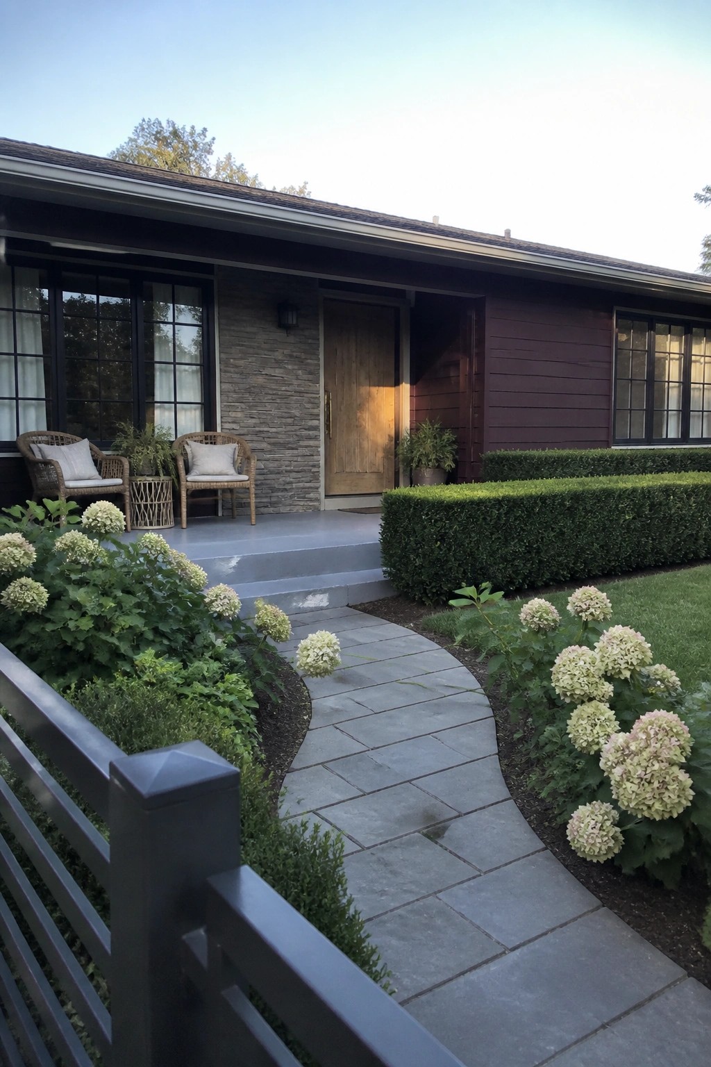 A ranch house exterior with plum siding, a stone accent wall beside the front door, and a curving stone walkway lined with hydrangeas.