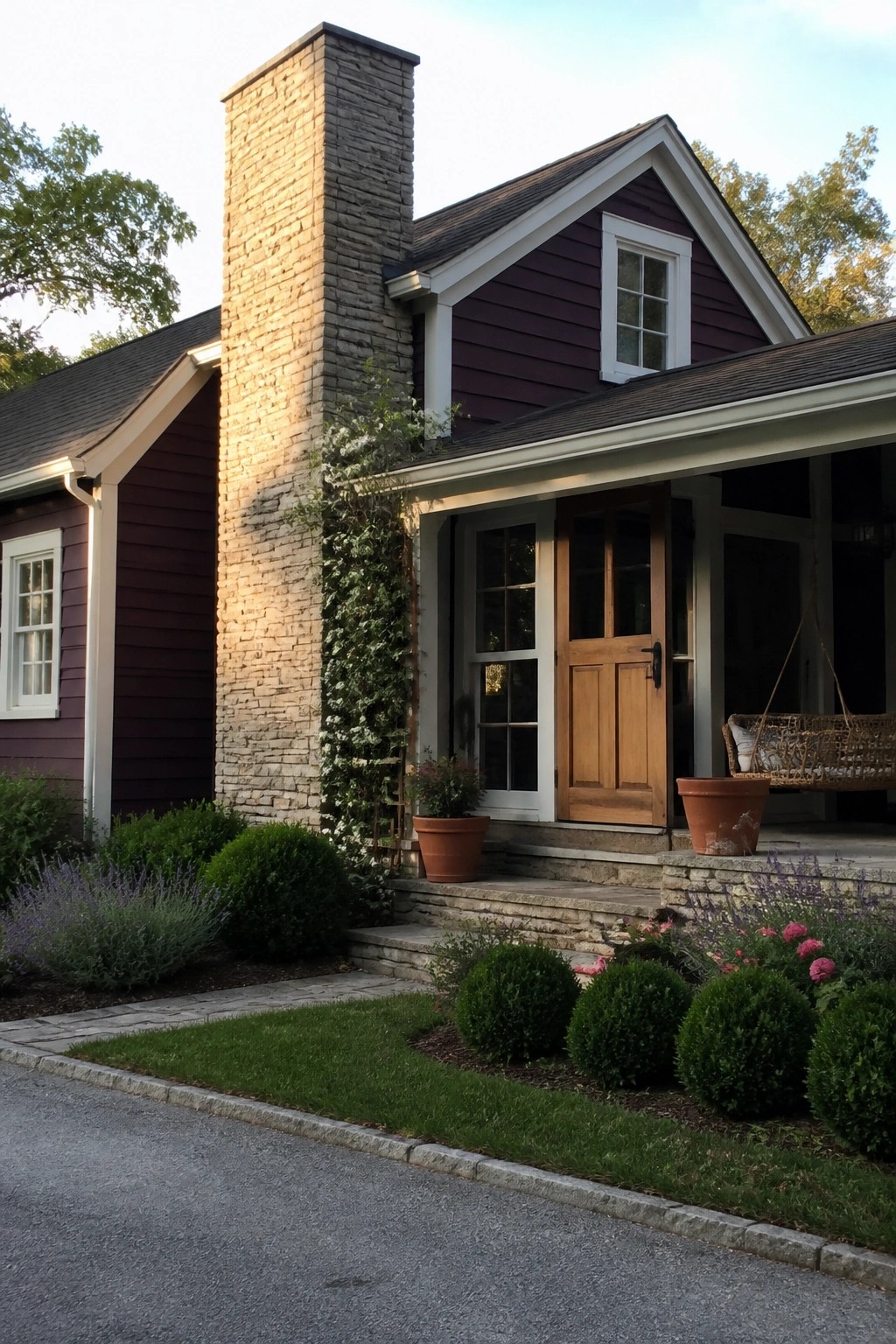 Purple house with stone chimney, wooden door, porch swing, and garden landscaping