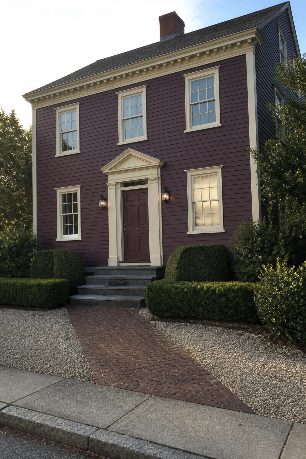 A two-story house with deep plum siding, cream trim, and a central entrance with steps and a brick path.