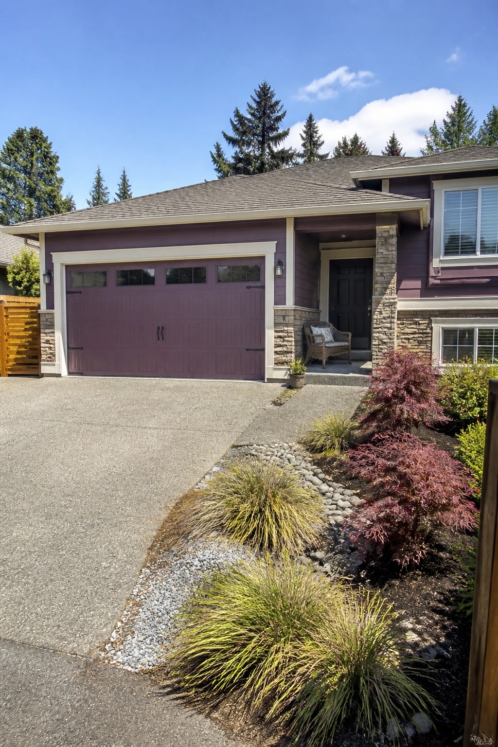 Purple garage door on house with stone accents and landscaped garden beds.