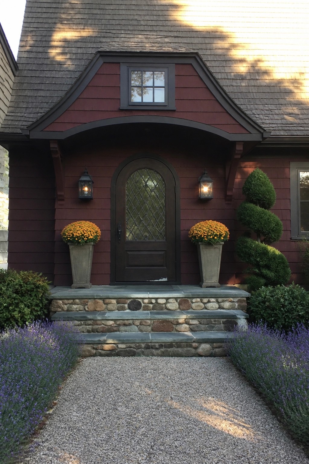 Red house entrance with arched wooden door, orange pots, lanterns and stone steps
