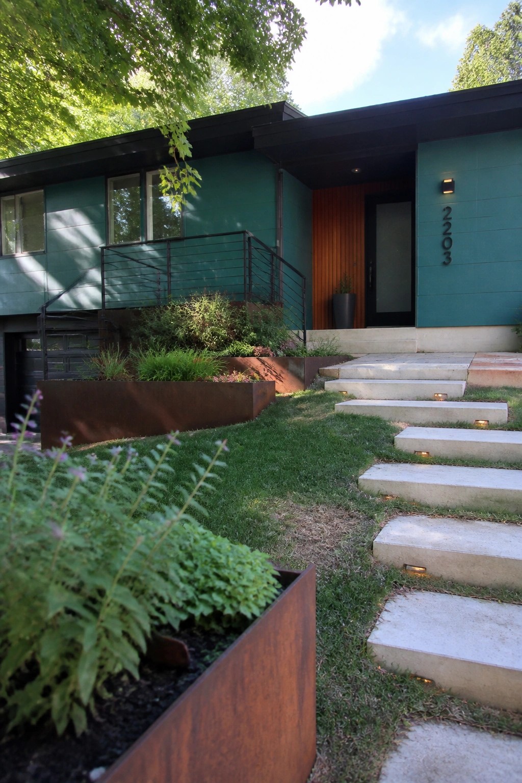 A modern two-story house with teal fiber cement panel siding, a vertical wood accent wall at the entry, and concrete steps leading to a black door.