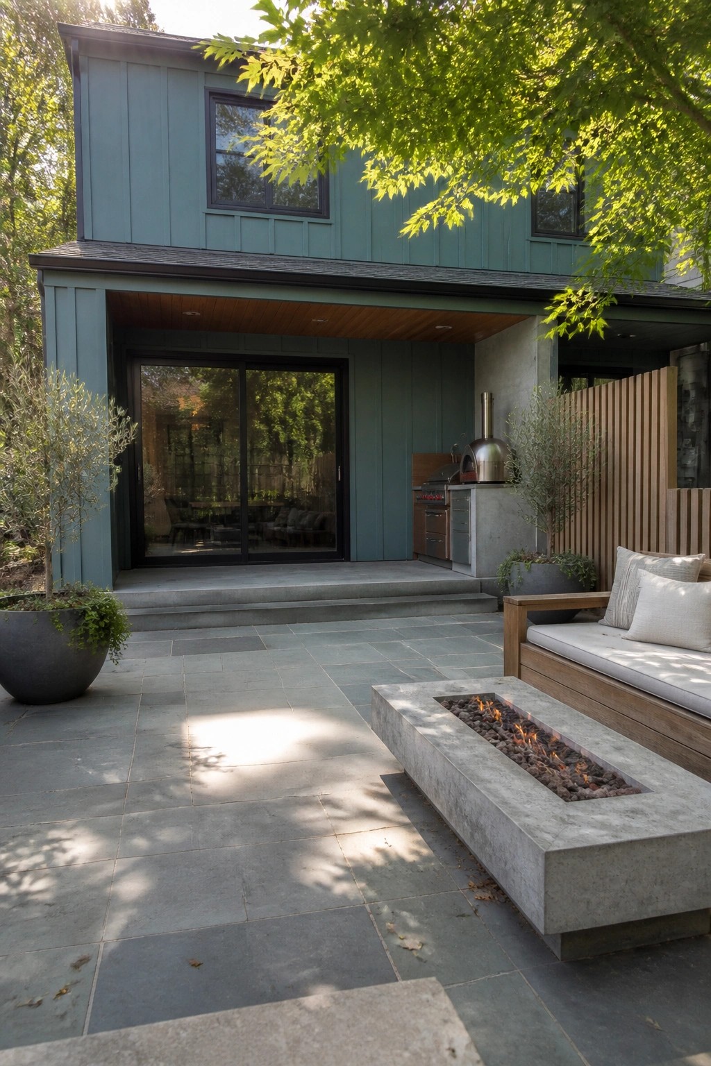 Modern teal house patio with concrete fire pit, wooden bench, and outdoor kitchen.