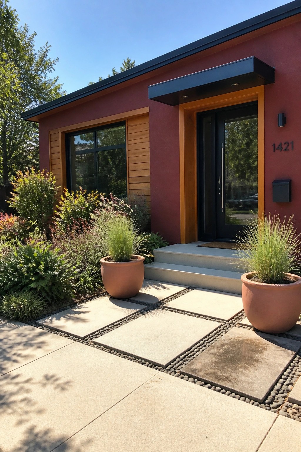 A burgundy house exterior featuring natural cedar wood trim around the black front door and a nearby window, with large terracotta pots placed beside concrete pavers.