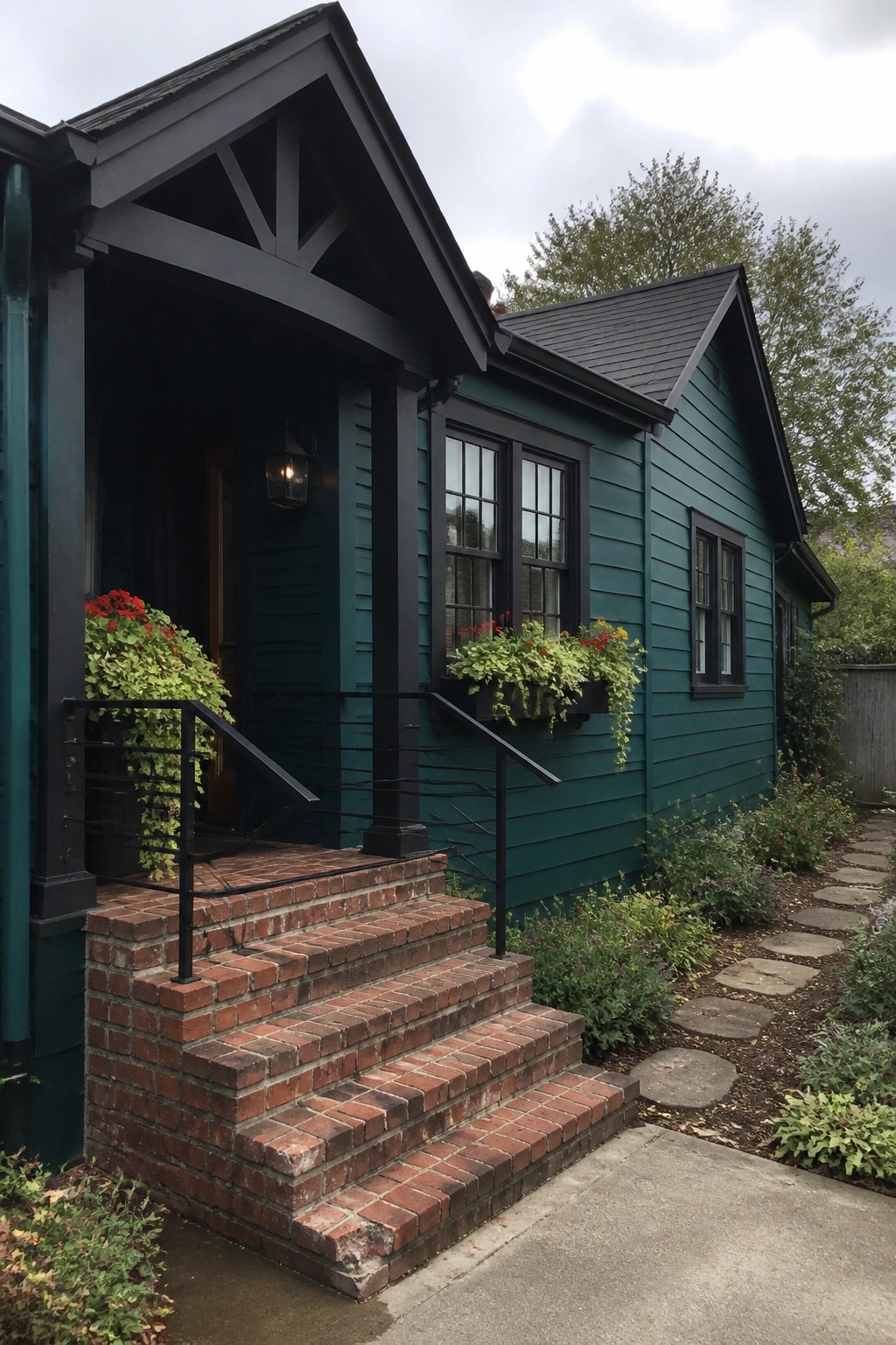 Teal house with black trim, brick steps, railings, and flower boxes.