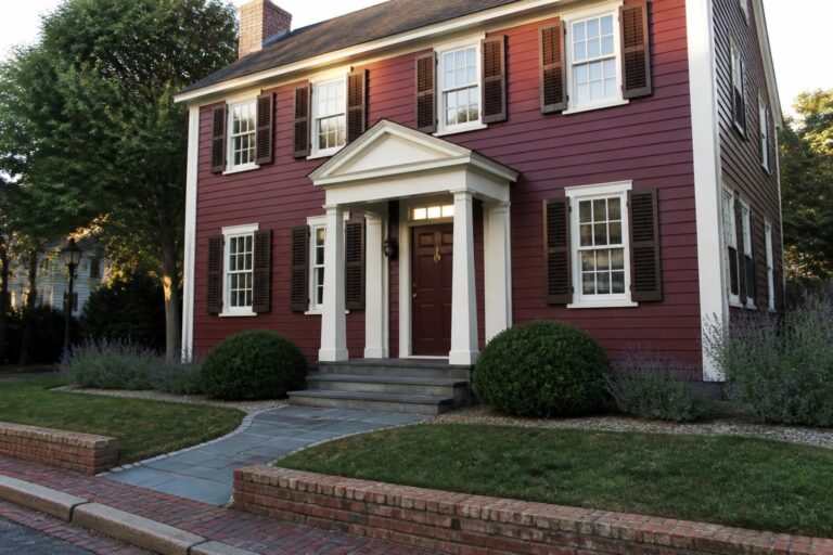 23 Elegant Maroon and White House Exteriors Paired with Crisp White Trim A two-story maroon house with white trim, dark shutters, and a white columned portico over the front door.