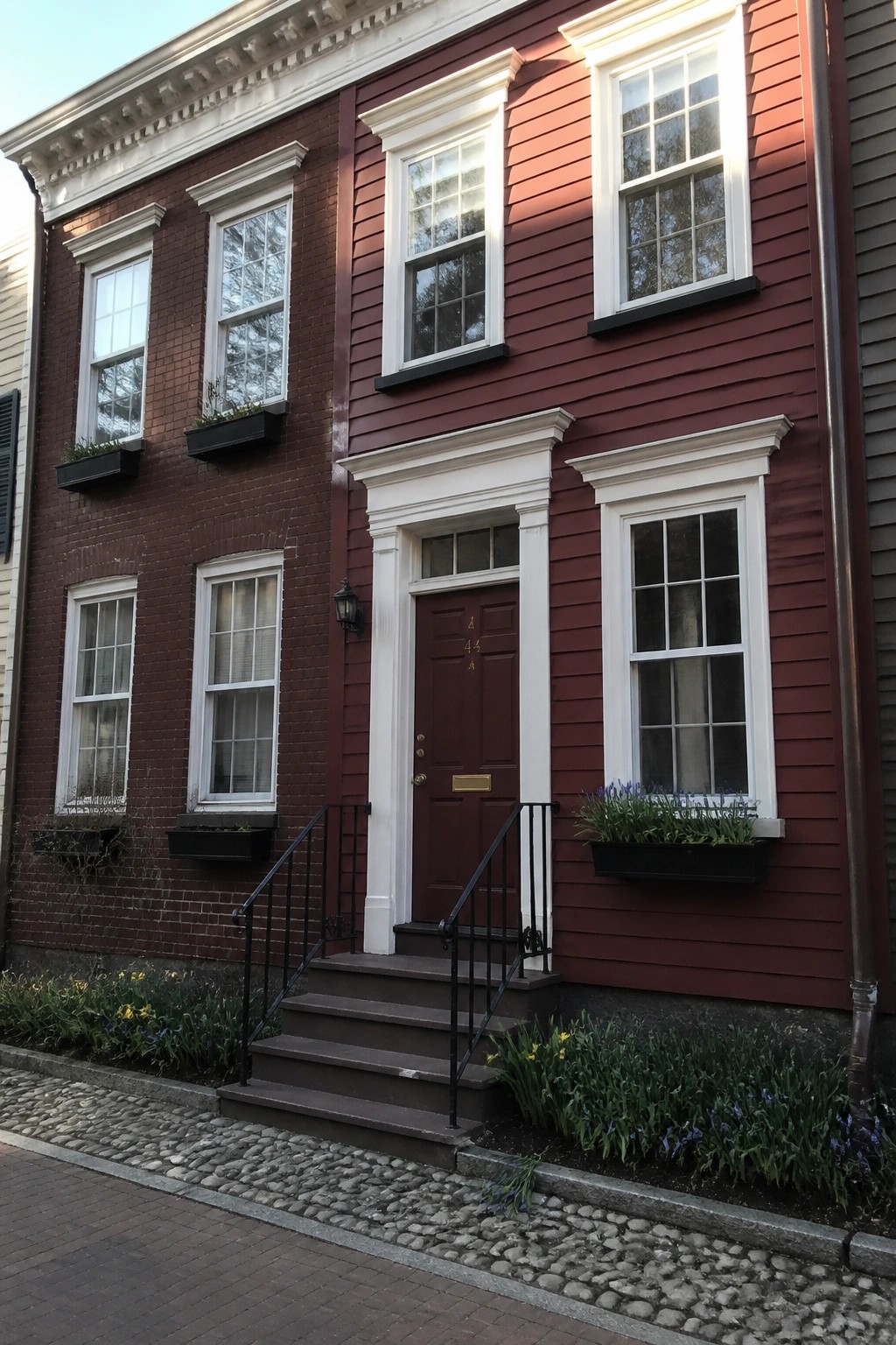 Red house with white trim, brown door, flower boxes, and front steps.