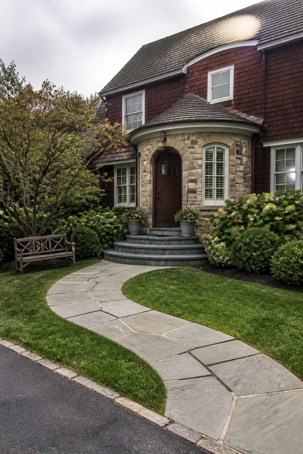 Curved stone path leads to brown door of red wooden house with garden