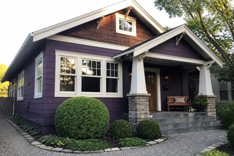 23 Striking Purple and White House Exterior Ideas Built Around High-Contrast Trim A house with purple siding, white window trim and eaves, a stone and wood porch column, and gray stone steps leading to the front door.