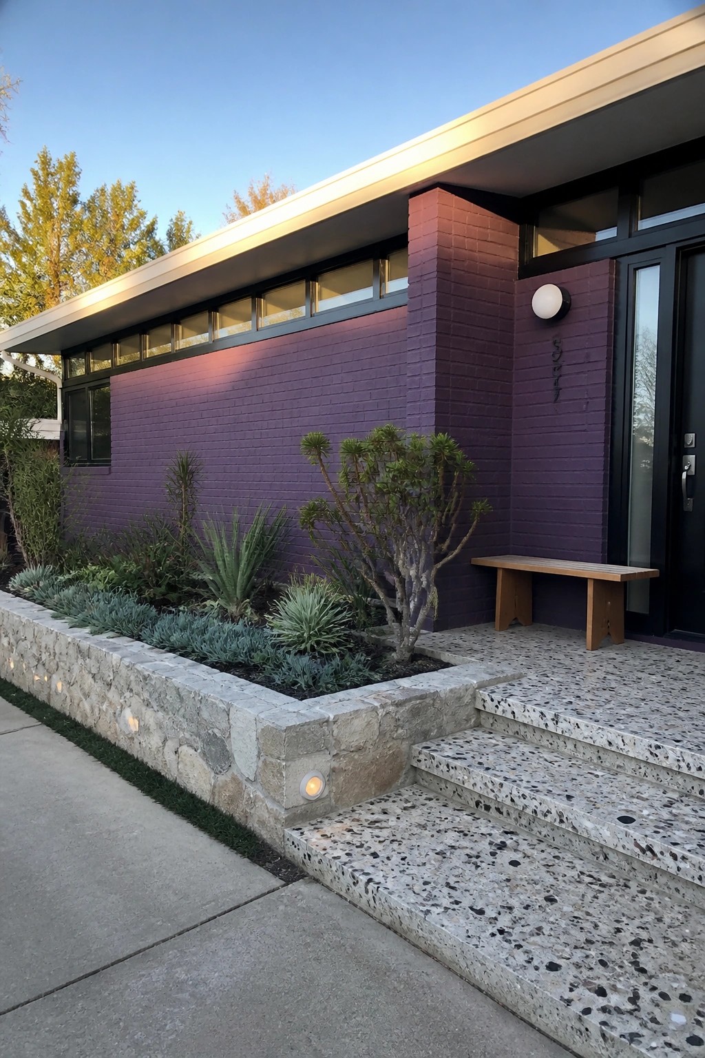 Modern purple brick house with stone planter, wooden bench, and terrazzo steps.
