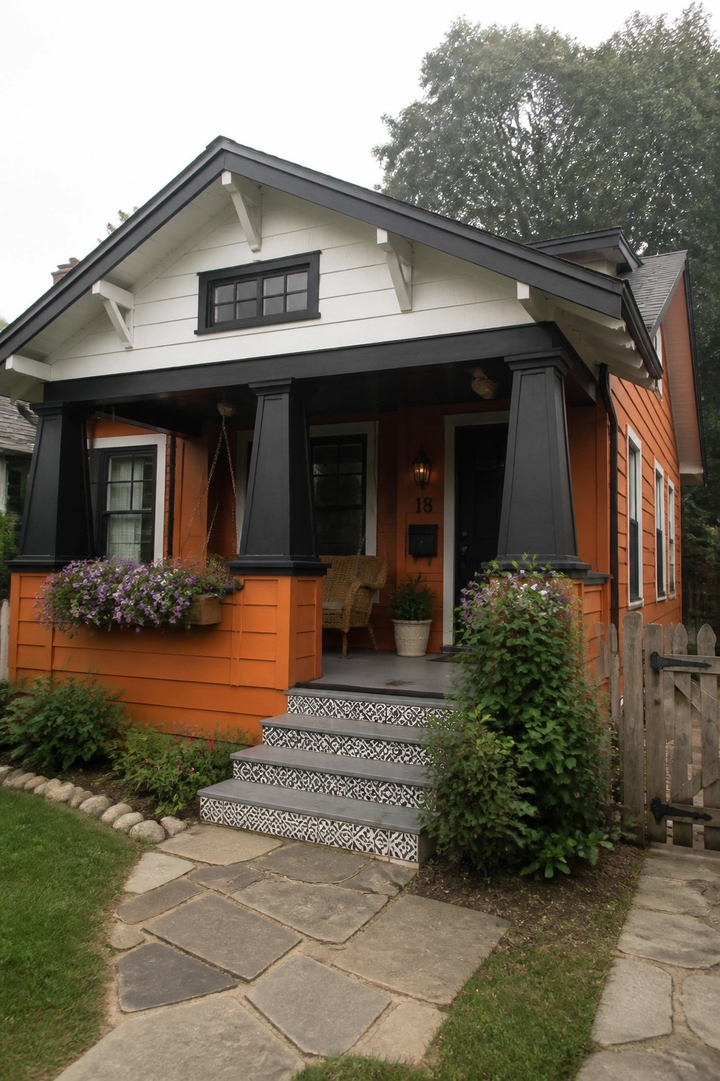 A small orange and white house with black trim, a covered porch, gray steps with patterned risers, and a stone path leading to the front door.