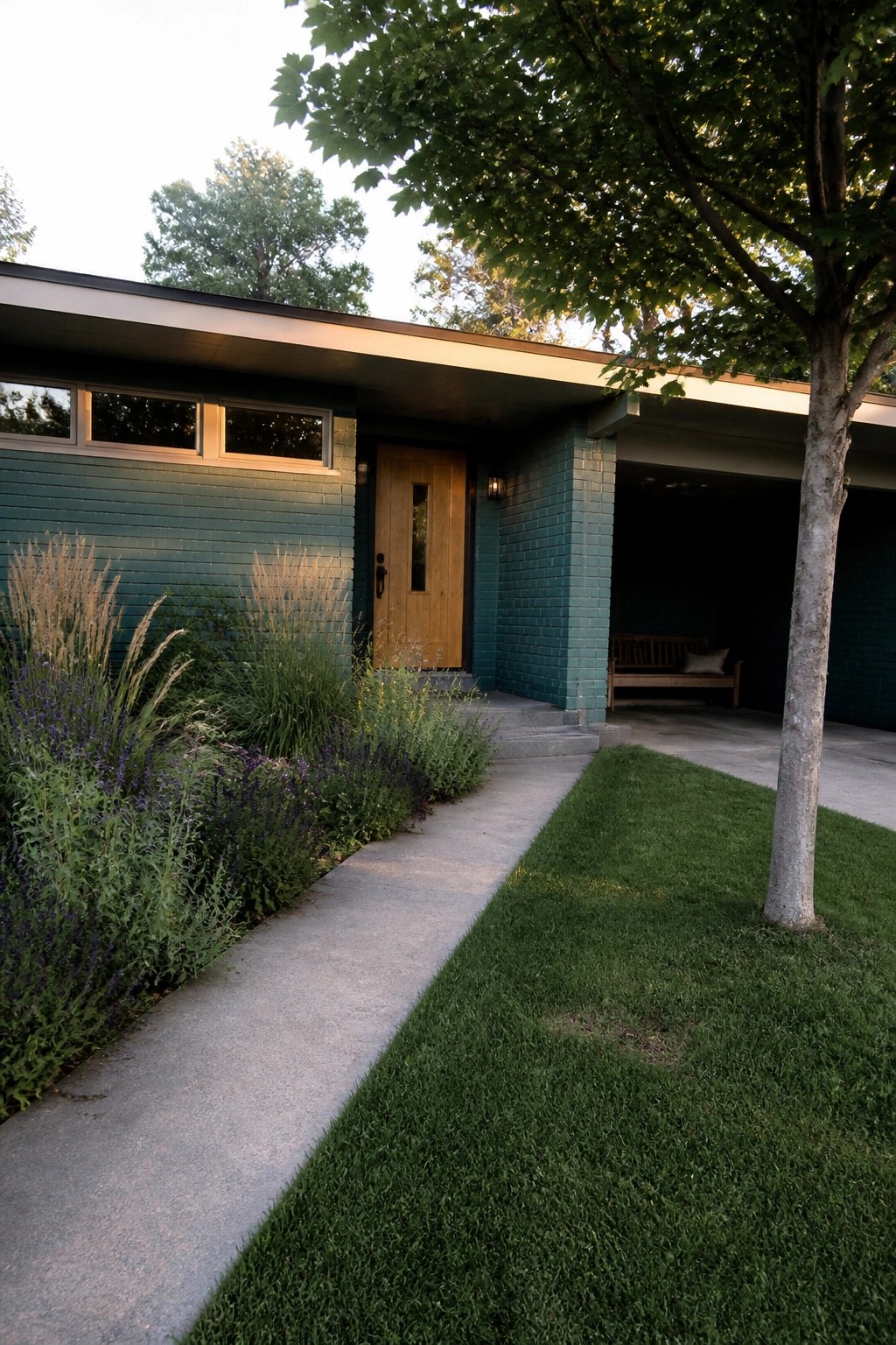 Concrete path to wooden door of teal house with lawn and plants