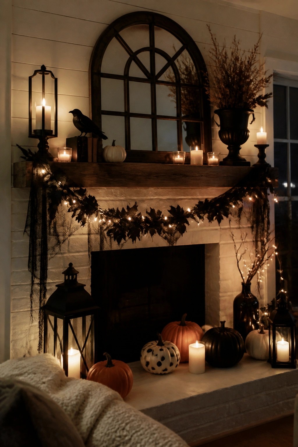 White brick fireplace with wooden mantel decorated with pumpkins, candles, lanterns, a black crow, and a leafy garland with string lights.