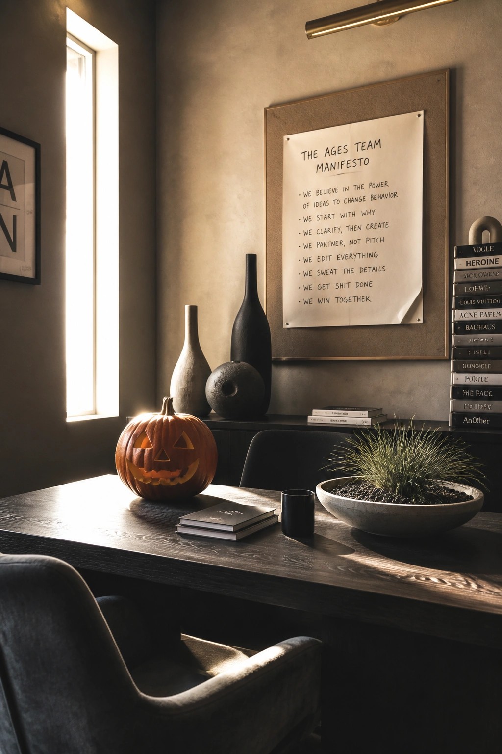 Lit jack-o'-lantern on wooden desk with manifesto poster, vases, and sunlight from window
