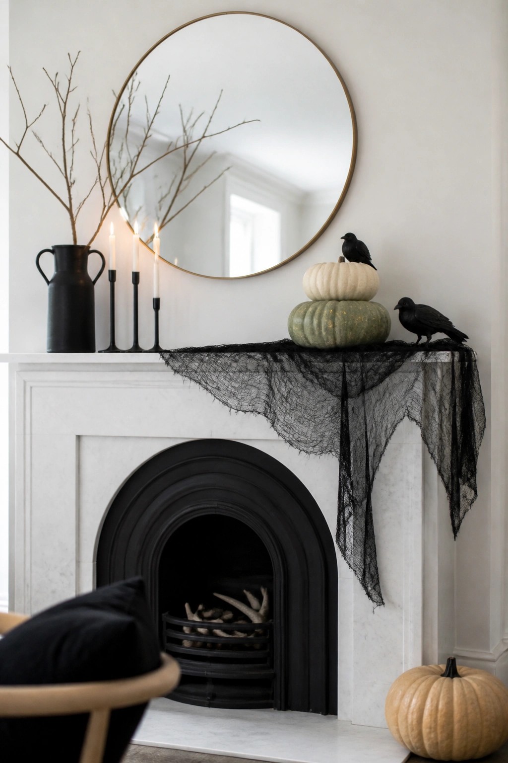 White fireplace mantel with stacked pumpkins, black crows, candles, and sheer fabric.