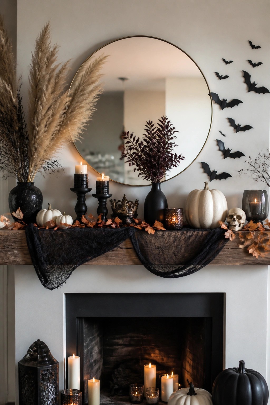 Fireplace mantel with black bats arranged around a round mirror, white and black pumpkins, candles, and a black fabric drape.
