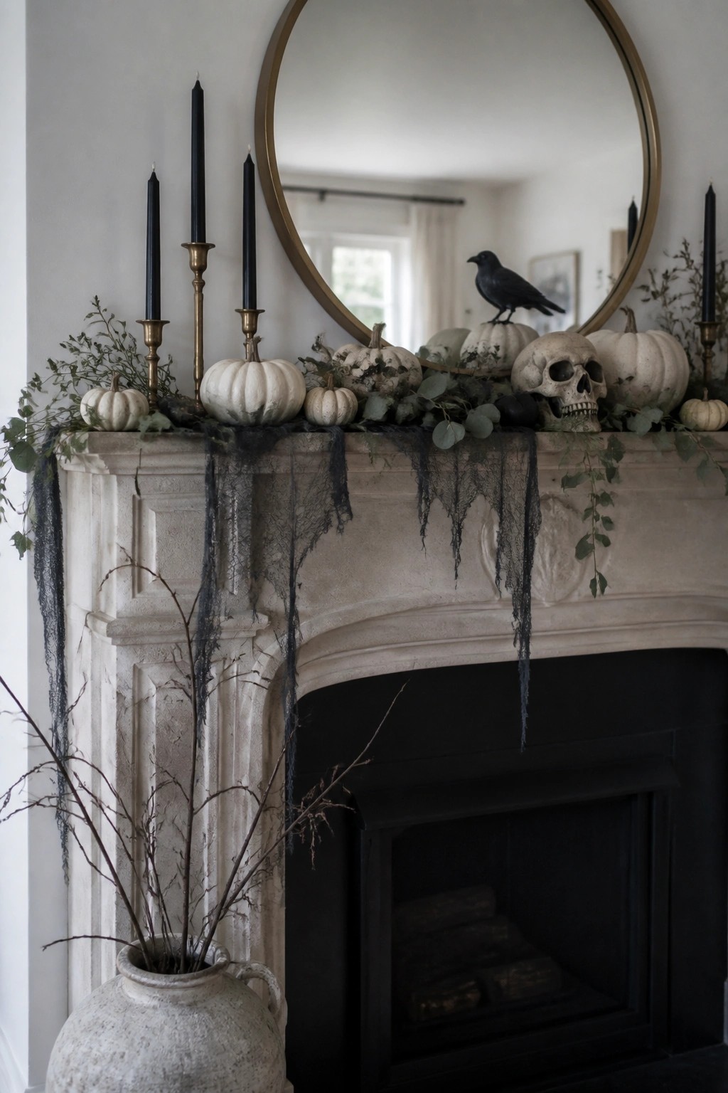 Fireplace mantel decorated with white pumpkins, a skull, a black crow, black candles, and dark fabric draped over the edge.