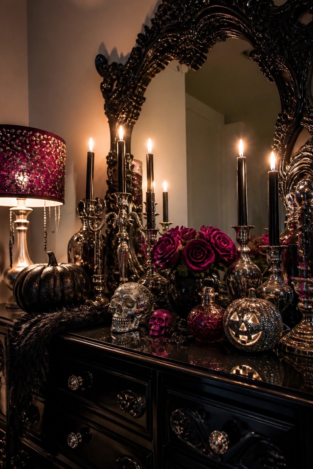 Black console table with glitter skulls, black taper candles in silver candlesticks, and small glitter pumpkins arranged in front of a large ornate mirror.
