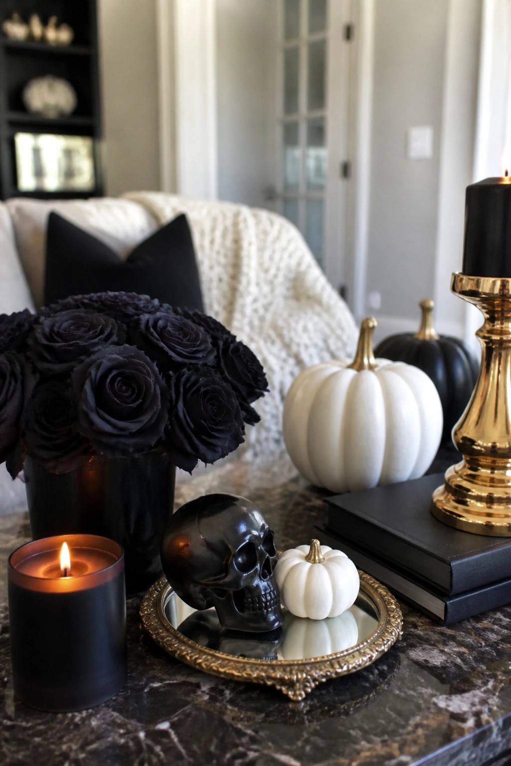 Black skull, roses, and pumpkins on marble table with lit candles