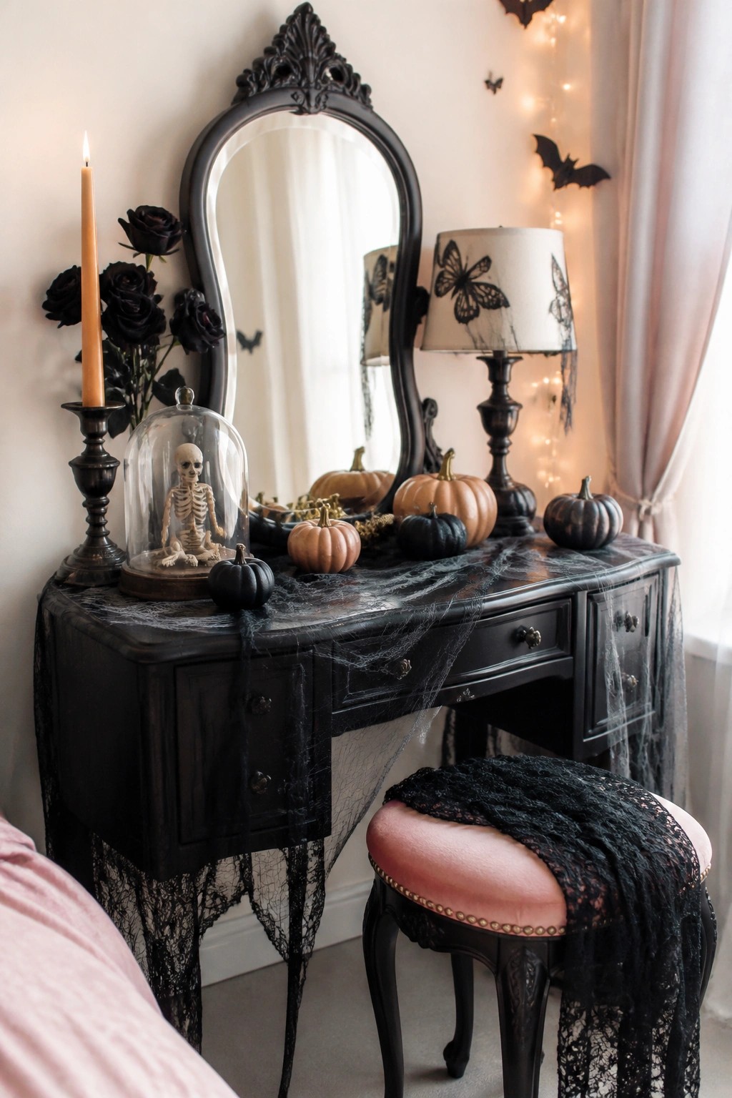 Black vanity table covered in fake spiderwebs with small pumpkins, a skeleton under a glass cloche, and black roses as a Halloween centerpiece.