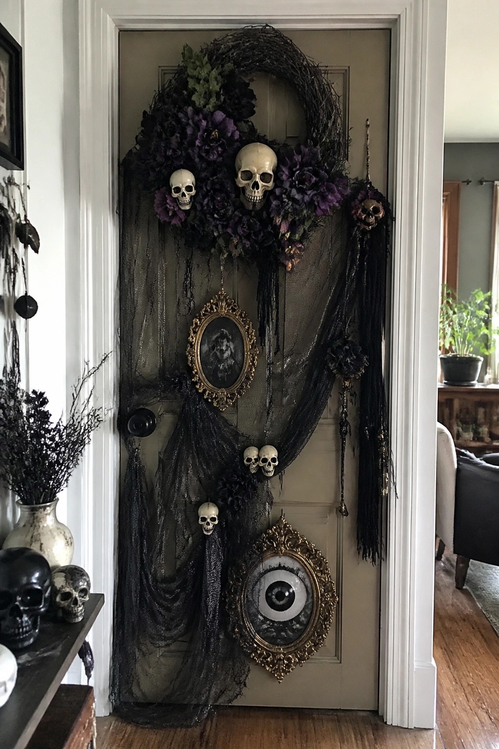 Interior door decorated with a large black wreath holding multiple skulls, black tulle draping, and a framed eye artwork below.
