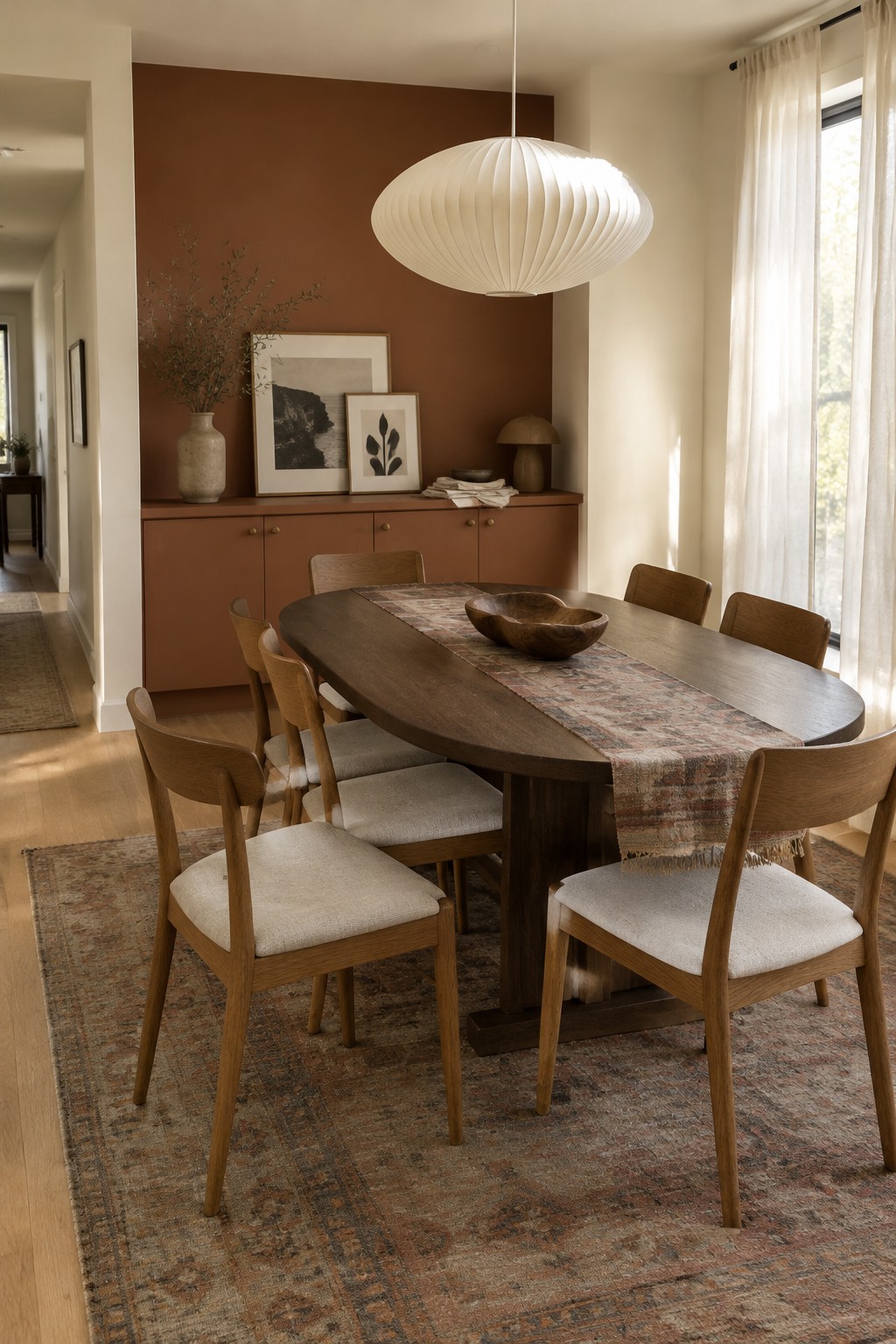 Rust-red walls and matching built-in cabinets in a dining room with warm wood furniture.