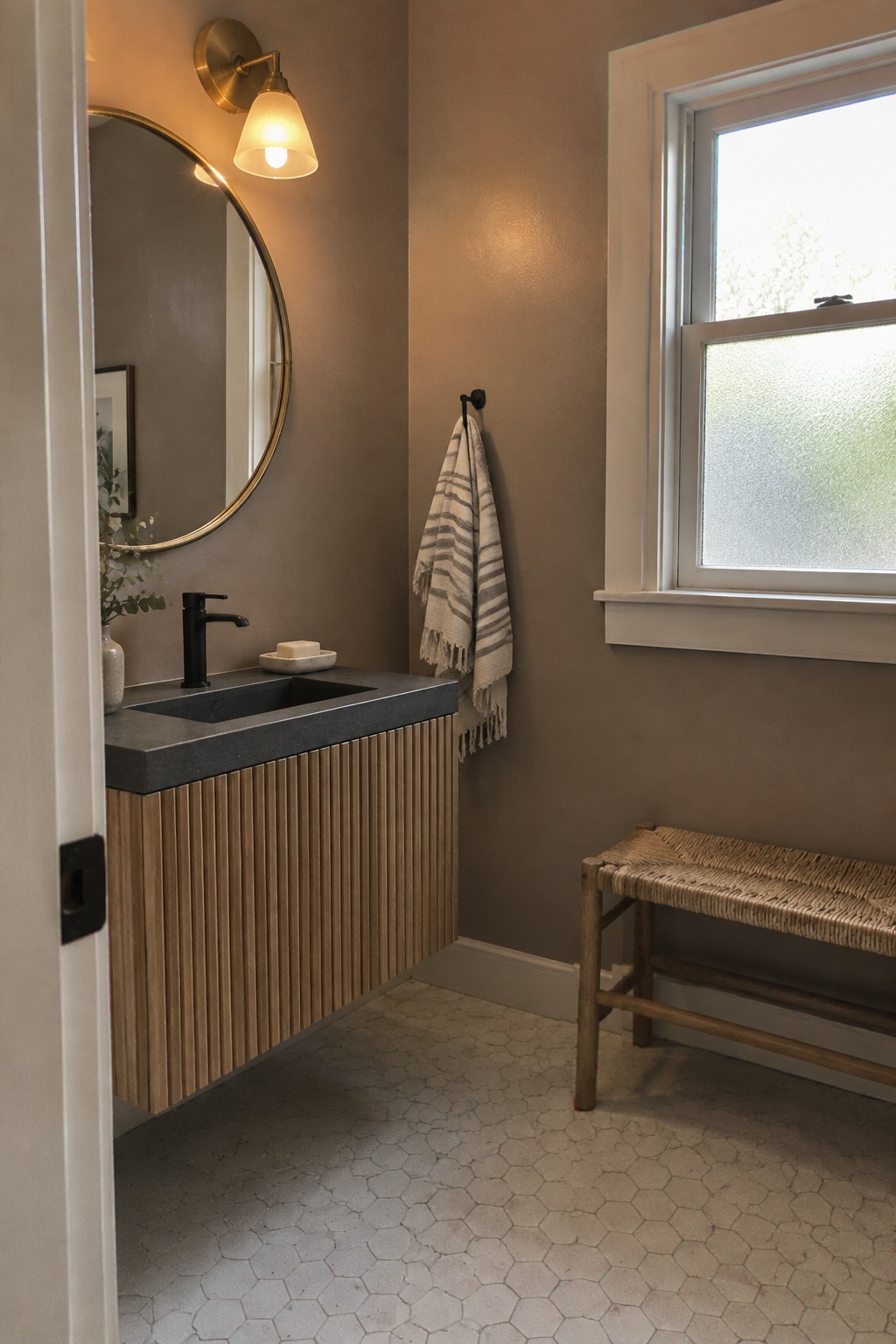Warm taupe bathroom walls beside a fluted oak vanity and dark stone countertop.